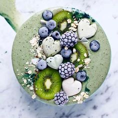 a green smoothie topped with kiwis, blueberries and raspberries