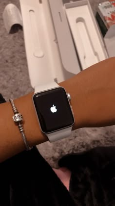 an apple watch on someone's arm in front of a box with other items