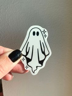 a hand holding a sticker with a ghost on it