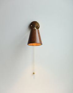 a wall mounted lamp with a brown shade on it's side and a white wall behind it