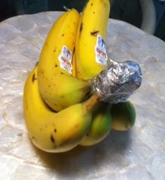 some bananas are wrapped in foil and sitting on a table with the caption, wrap the top of your bananas with plastic wrap and they'll last four to five