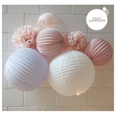 pink and white paper lanterns hanging from a brick wall