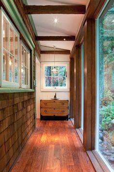 an empty room with wood floors and windows on the wall, along with a wooden dresser