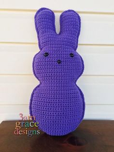 a crocheted purple bunny sitting on top of a wooden table