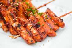 chicken skewers with sesame seeds and garnishes on a white plate