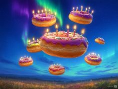 a birthday cake with lit candles floating in the air over other cakes and donuts