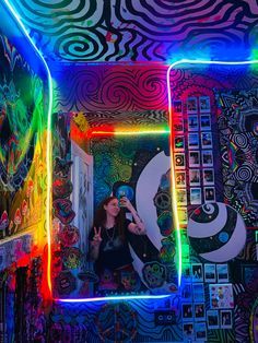 a woman taking a selfie in a room with neon lights on the ceiling and walls