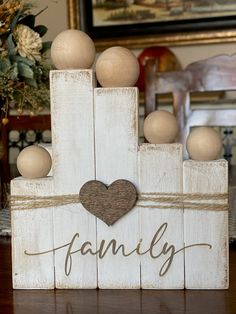 a wooden block with the word family painted on it and some balls in the shape of a heart