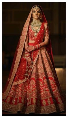 a woman in a red and gold bridal gown, standing with her hands on her hips