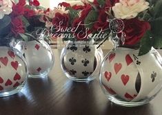 four vases with hearts and playing cards on them sitting on a table next to flowers