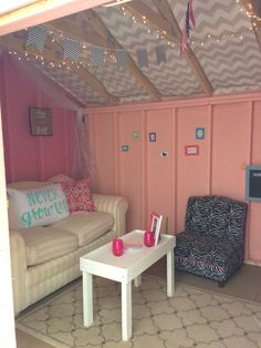 a living room with pink walls and white furniture in the corner, decorated with string lights