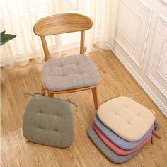 four different colored cushions sit on the floor next to a chair