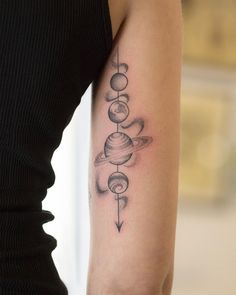 a woman with a tattoo on her arm that has planets and arrows in the middle