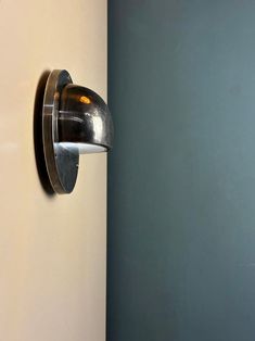 a wall mounted light on the side of a white wall next to a blue wall