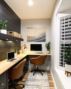 a home office with two computer desks and a plant in the window sill