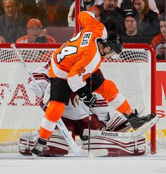 two hockey players in orange and white uniforms on the ice