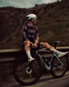 a man sitting on top of a bike next to a road