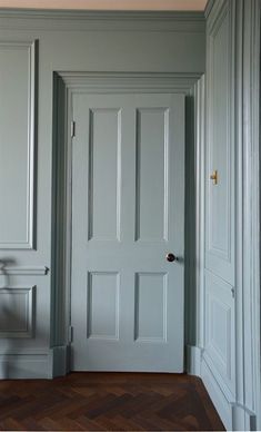 an empty chair sits in front of the door to a room with gray walls and wood floors