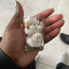 a hand holding a shot glass filled with white and gold glittered rocks in it