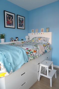 a bedroom with blue walls, white furniture and pictures on the wall above the bed