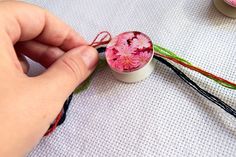 a person is sewing flowers on a piece of fabric with scissors and thread in the background