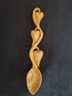 a wooden spoon with two hearts carved into it's sides on a black surface