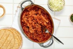 a pot full of pulled pork and tortilla chips on a white tiled counter