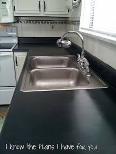 a kitchen with white cabinets and black counter tops, stainless steel sink and dishwasher