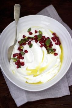 a white bowl filled with cream and pomegranate on top of a wooden table