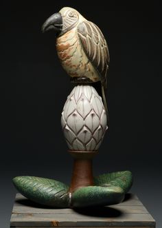 a ceramic bird sitting on top of a vase