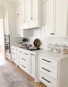 a kitchen with white cabinets and an area rug