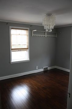 an empty room with hard wood floors and a chandelier