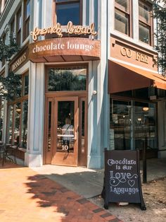 the front entrance to a chocolate lounge with a chalkboard sign in front of it