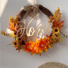 a wreath with the word home hanging on a wall next to a straw hat and sunflowers