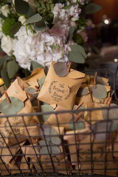 a basket filled with lots of small brown tags next to a bouquet of white flowers