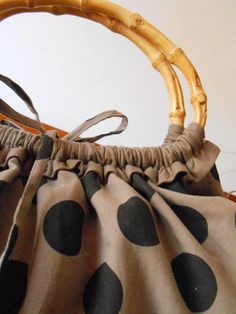 a brown and black polka dot purse sitting on top of a wooden chair next to a wall