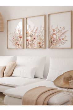 three paintings on the wall above a white couch with pillows and throw pillows in front of it