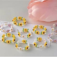 several bracelets with flowers and pearls on them sitting next to a pink flower bouquet