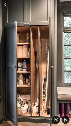 an open cabinet in the corner of a kitchen with lots of cleaning supplies and tools