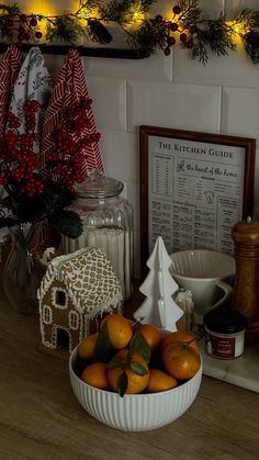 a bowl filled with oranges sitting on top of a counter next to christmas decorations