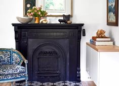 a living room with a fireplace, chair and pictures on the wall above it's mantle