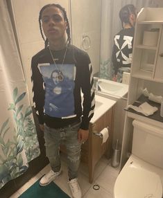 a young man standing in front of a bathroom mirror next to a toilet and sink