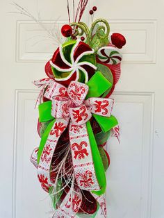 a red and green christmas wreath hanging on a door with candy canes in it