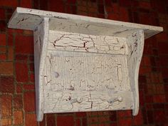 an old white wooden shelf on a brick wall with red bricks in the back ground