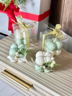 two small glass vases filled with eggs and greenery on top of a table