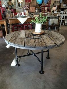 a wooden table with metal legs and a potted plant on top