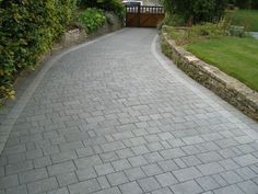 a brick walkway in the middle of a garden with green grass and bushes on either side