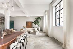 a living room filled with furniture and lots of windows next to a long wooden table