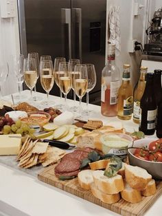 several glasses of wine, cheese and meat on a cutting board with other food items