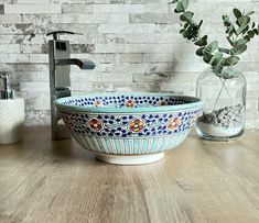 a blue and white bowl sitting on top of a wooden table next to a faucet